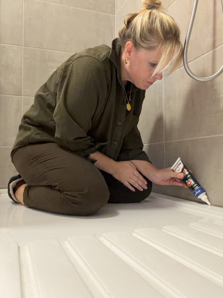 Georgina Bisby applying Dryzone mould-removing gel to a bathroom shower seal to treat autumn damp and mould