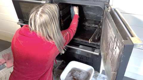 Wiping down the inside of the oven after the baking soda paste has broken down the grease